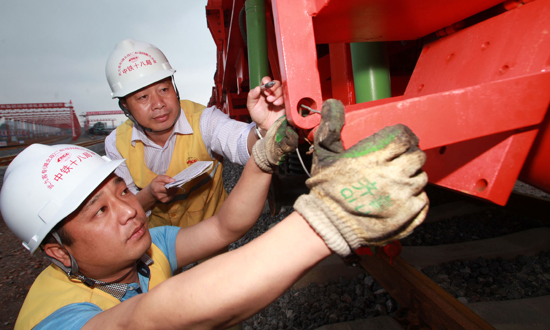 锃亮的鋼軌筆直地向前延伸著，橘黃色的鋪軌機“四平八穩”地行駛在楚天大地，現場忙碌的工人們揮汗如雨……他們為了企業榮譽，項目經理韓少華（左）、項目書記羅謙（右）帶領大家發揚“特別能吃苦、特別能戰斗、特別能奉獻”的鐵道兵精神，堅守施工一線。從寒冬臘月直到春暖花開，他們每天在現場風餐露宿。為保質保量按期開通新線，就連春節都沒有放假。（伍振 攝）