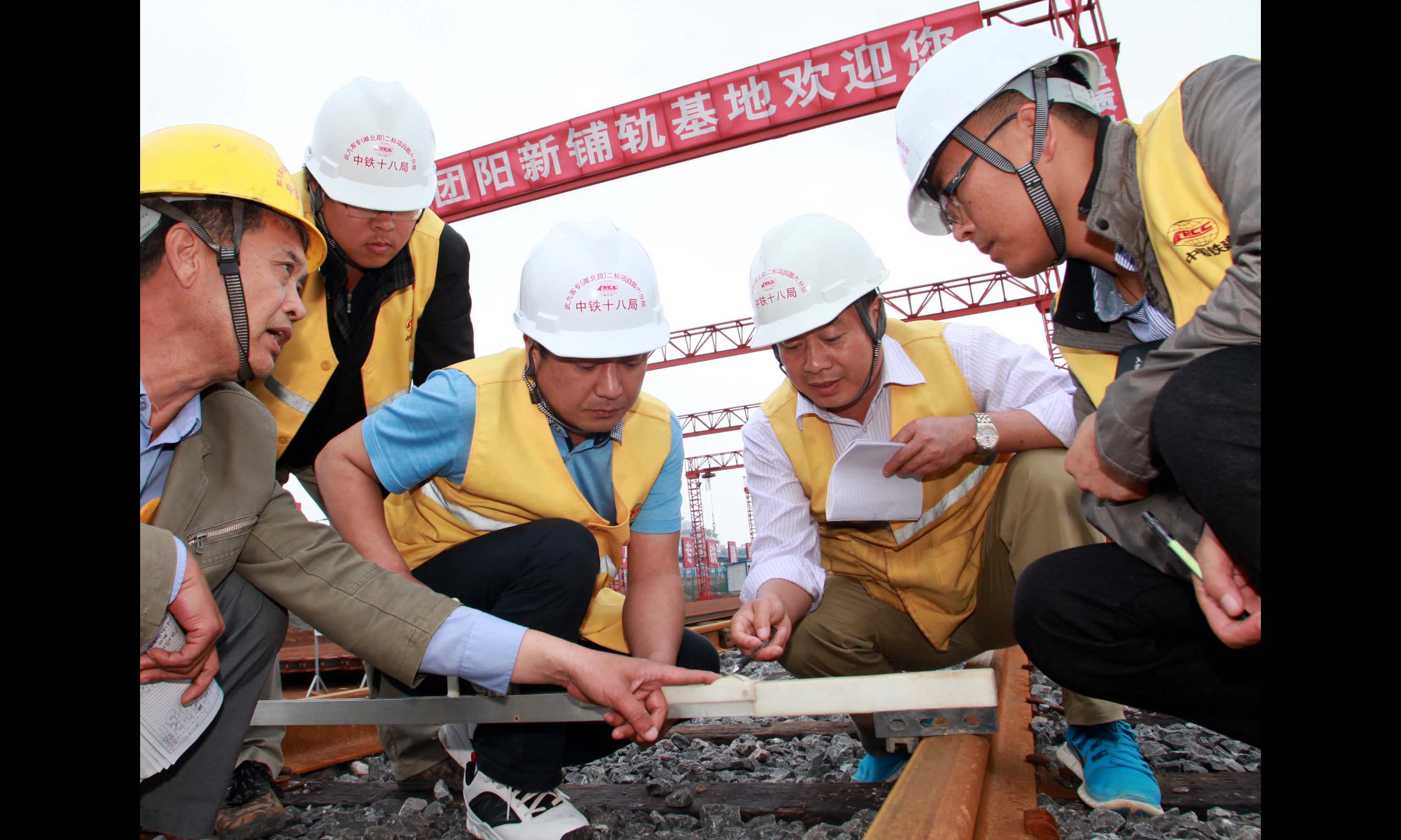 每一次大機搗固作業完成以后，施工人員都要對全線進行一次檢測。由于客運專線對軌距的正負誤差要求必須控制在1毫米以內，所以對于線路上的數萬根枕木，項目總工毛永明及相關測量人員要用電子道尺逐根測量軌距。每走一步，他們就要低一次頭、彎一次腰，就像虔誠的教徒朝拜一樣。夜以繼日，風雨無阻，凹凸不平的石砟上，一走就是10多個小時，腳上的血泡好了又起，鞋子踩壞了一雙又一雙。一份拼搏，一分收獲。中國鐵建十八局集團2016年上半年全線信用評價第一名，另外多次綜合評比名列前茅，建設者們在“長江經濟帶”譜寫了鐵路建設新傳奇……（伍振 攝）