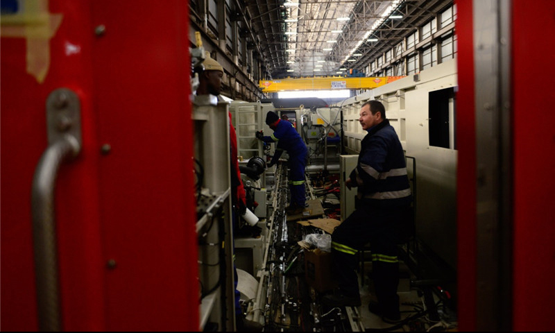 自2012年10月以來，中車株機公司與南非運輸集團先后簽署了195臺四軸電力機車和359臺六軸電力機車的供應合同，合同金額近24億美元，是中國軌道交通裝備行業出口的最大訂單。圖為7月27日，在南非比勒陀利亞南非運輸集團工廠組裝車間，當地技術人員在一臺待組裝的中國機車里工作。（新華社記者 翟健嵐 攝）