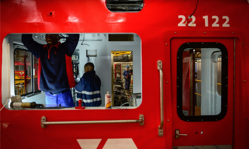 這是7月27日，在南非比勒陀利亞南非運輸集團工廠組裝車間，中南兩國技術人員對一臺待組裝的中國機車司機室進行內部裝飾。（新華社記者 翟健嵐 攝）