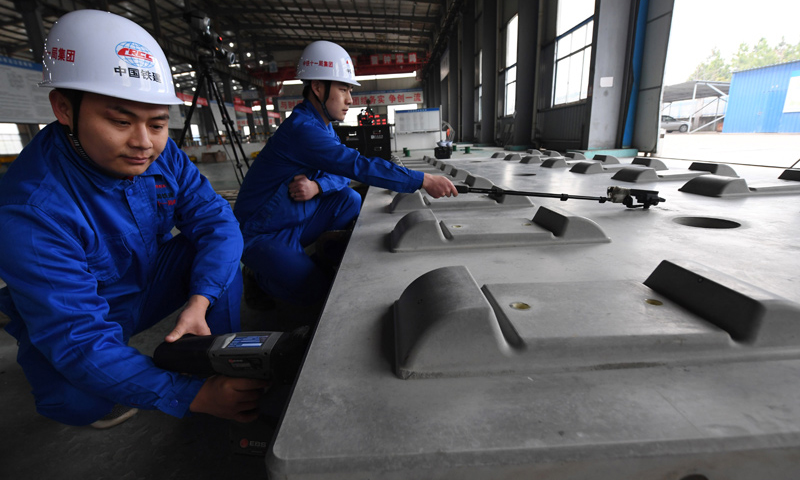 2018年1月22日，王偉（左）用手持式噴碼槍在給CRTSⅢ型先張法軌道板進行激光打碼。（新華社記者 宋振平 攝）