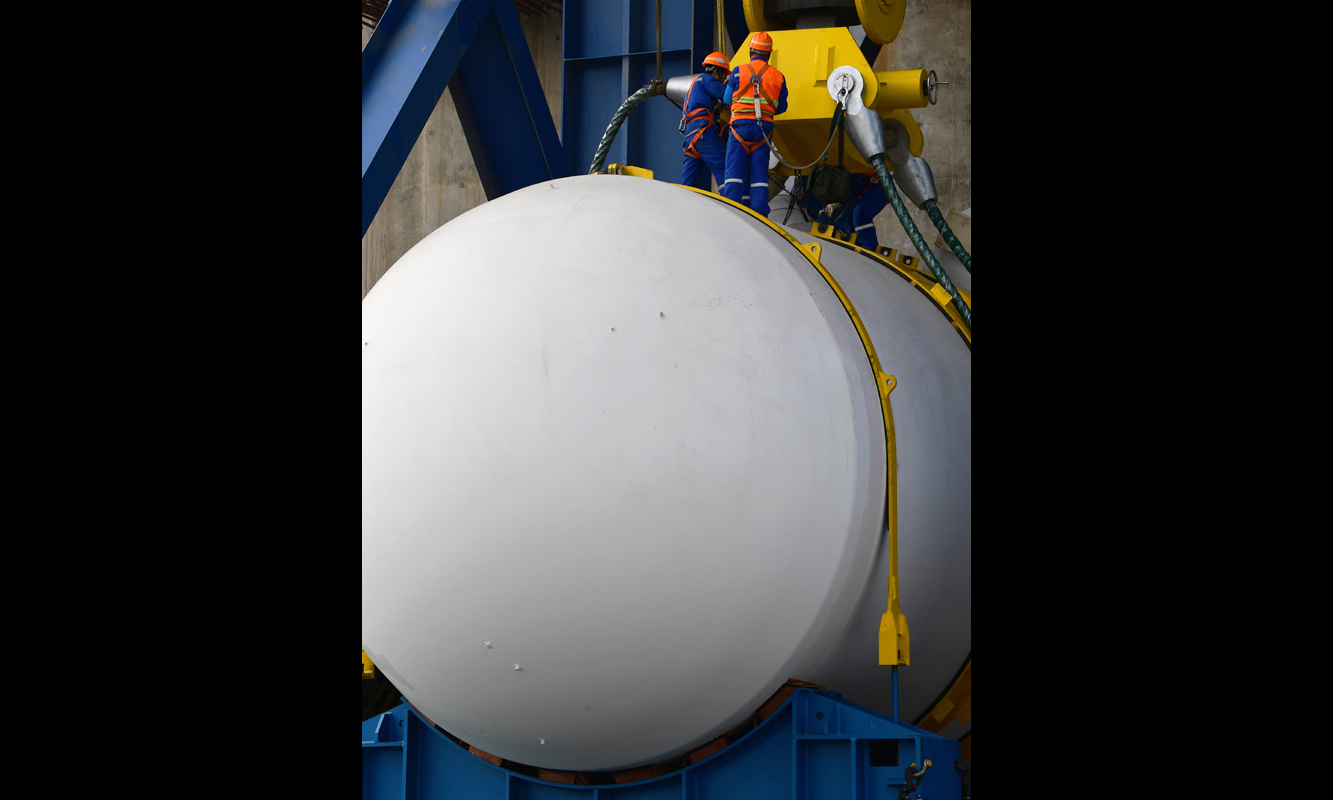 與二代改進型機組相比，“華龍一號”示范工程壓力容器采用全新177堆芯結構設計，設計壽命由40年延長到60年，抗震要求從0.2g提高至0.3g，安全性得到提升。圖為2018年1月17日，在福清核電5號機組反應堆廠房龍門架下，工作人員準備吊裝反應堆壓力容器。（新華社記者 魏培全 攝）