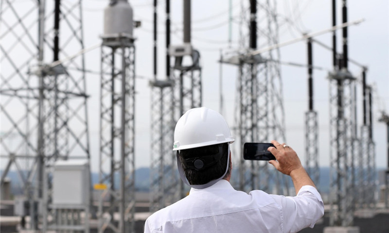 12月21日，在巴西米納斯吉拉斯州伊比拉西市，一名當地參會者在埃斯特羅托換流站拍照留念。（新華社記者 李明 攝）