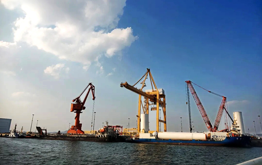 大連莊河海上風電項目位于大連莊河石城島東側約11公里處海域，場址中心距離岸線約19.1公里。施工任務主要包括40根6.0米—6.8米非嵌巖單樁鋼管樁風機基礎施工和60臺5兆瓦的風力發電機組安裝施工，總裝機容量為300兆瓦。圖為風機塔筒和風機配件組裝出運。