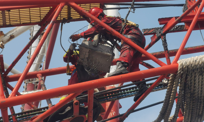 圖為在第19號臺風“天鵝”來臨前，“COSLCRAFT”鉆井平臺電氣師正在對吊車扒桿照明燈進行加固。