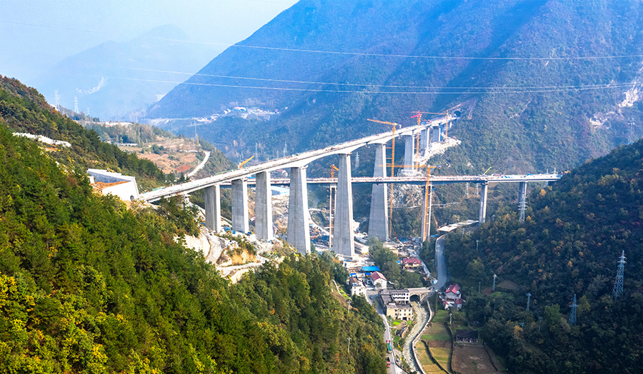據悉，該橋位于湖北省保康縣境內荊山、神農架林區溝谷接合部，全長668.36米，最大墩高111米，為鄭萬高鐵第一高墩。橋梁上跨既有省道且與新建保神高速兩河口大橋同期作業，施工組織難度、安全管控風險呈現“雙高”。圖為鄭萬高鐵湖北段兩河口雙線大橋全橋合龍。（張慧 攝）