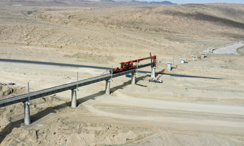 目前，國家重點工程——格庫鐵路（青海格爾木至新疆庫爾勒）新疆段按照節點有序推進鋪架作業，橋梁和軌排已生產完畢，焊軌工作全面展開。圖為7月18日，中鐵一局的施工人員跨315國道進行架梁作業。（新華社記者 丁磊 攝）