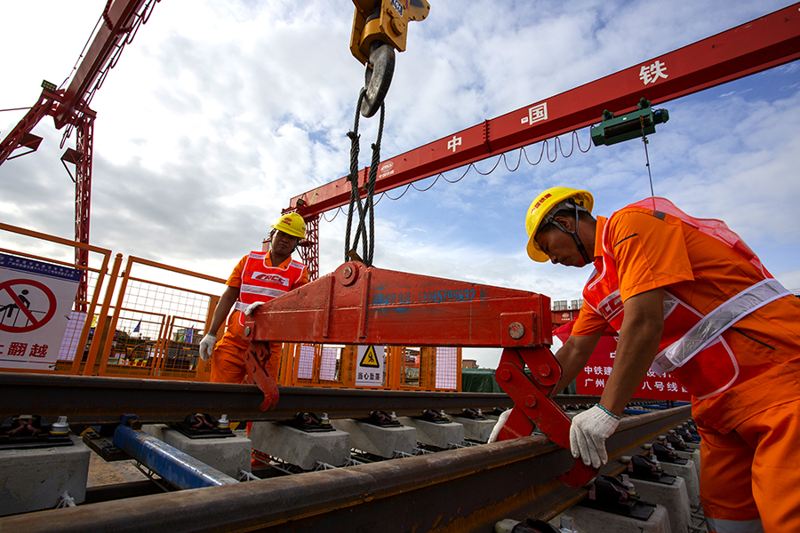 廣州地鐵十八號線線路全長61.3公里，起始于南沙萬頃沙樞紐，止于天河廣州東站，途徑南沙區、番禺區、海珠區及天河區，設9站8區間。其中，9座車站有8座車站為換乘站，最長站間距達25.9公里，為橫瀝至番禺廣場區間，這是目前國內站間距最大的地鐵區間。圖為作業人員正在掛軌排吊鉤。（彭特 攝）