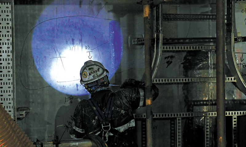 由于艙室內部照明不足，工人刷漆時安全帽上會裝一個頭燈用于補光。