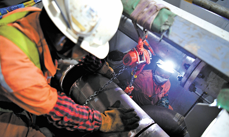 6月29日早7時許，滂沱大雨中，霧氣籠罩的中國海油青島場地上，陵水17-2半潛平臺船體四條“擎天巨臂”的最后一個“關節”完成吊裝。至此，我國首個1500米深水半潛平臺船體提前16天完成結構封頂，為船體陸地建造完工贏得了寶貴的時間。圖為船體內部，作業人員進行管線對接作業。