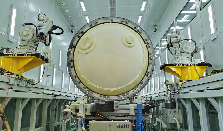 近日，航天科技集團八院149廠低溫貯箱絕熱層自動磨削工藝鑒定方案順利通過工藝評審，并成功應用于運載火箭低溫貯箱研制生產。149廠針對絕熱層手工打磨方式存在厚度波動大、工作效率低等問題持續進行技術創新。據了解，該設備突破了大型貯箱快速掃描建模、橢球形曲面刀具避障路徑編程、大直徑貯箱姿態快速調整等關鍵技術，實現了直徑液氧貯箱箱底和筒段聚氨酯泡沫塑料厚度可控穩定性加工，磨削加工效率可以提高100%以上。圖為低溫貯箱絕熱層正在進行自動磨削加工。