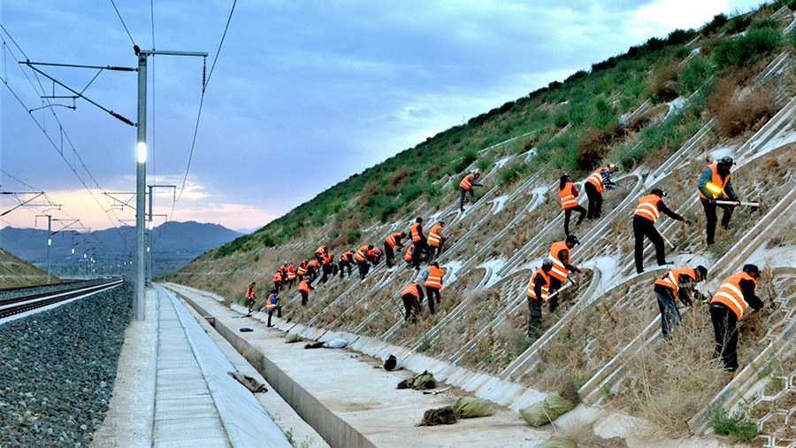 在中鐵二十局承建的崇禮鐵路二標施工現場一派繁忙。彼時，項目參建者正克服既有線施工安全風險大、氣候環境惡劣等困難，補種苗木4萬株，為綠色生態冬奧奠定堅實基礎。圖為參建工人對路基邊坡進行綠植施工。（曲志忠 攝）