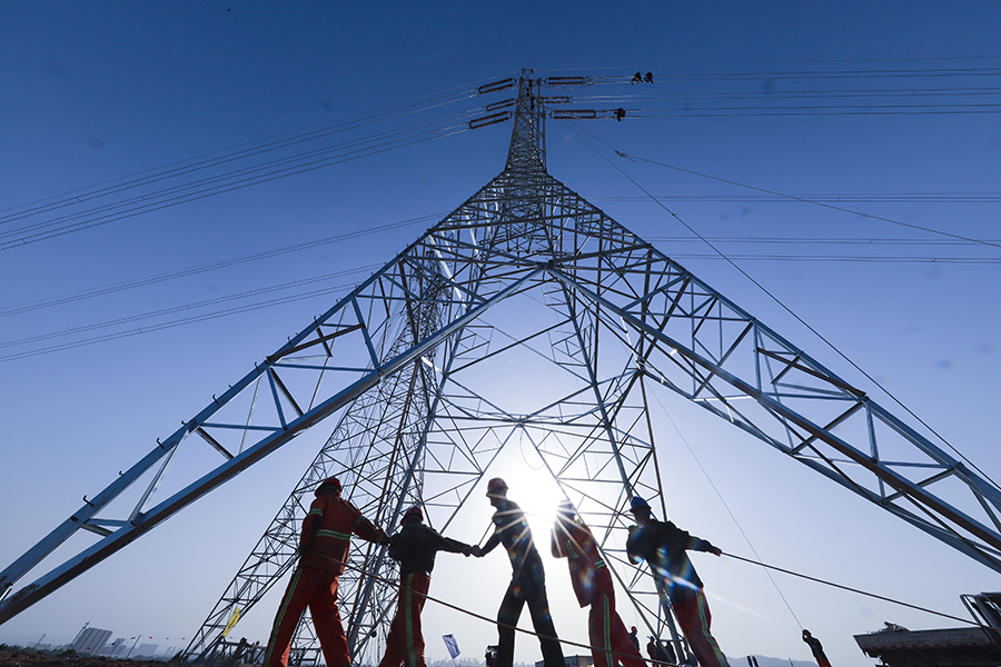 圖為工人齊心協力在鐵塔下施放導線。（范成濤 攝）