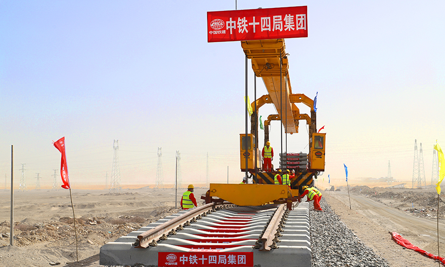 和(田)若(羌)鐵路位于新疆維吾爾自治區南部和田地區和巴音郭楞蒙古自治州境內，是國家《中長期鐵路網規劃》中的重要鐵路干線。線路從南疆鐵路和田站引出，經洛浦、策勒等縣市，東至巴州若羌縣，全長825公里，為單線鐵路，設計時速120公里，為客貨兩用鐵路線。建成后將與在建的格庫鐵路組成新疆第三條東西向交通大干線和國際大通道，并與格庫鐵路、南疆鐵路相連在塔里木盆地周邊形成一條環形鐵路網，也將是世界首條繞沙漠環形鐵路網。圖為首組軌排精準落位。