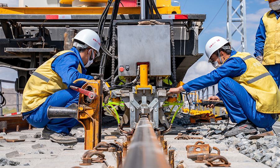 “焊接好的鋼軌，將通過應力放散鎖定、大機精搗、線路精調等作業，最大限度地提高行車面的平順度，在列車高速行駛過程中，保證旅客乘坐的平穩和舒適。”中國鐵建所屬中鐵十一局三公司拉林鐵路項目經理沈育斌介紹道。圖為施工人員對焊接好的鋼軌準備正火工序。（丁慶濱 攝）