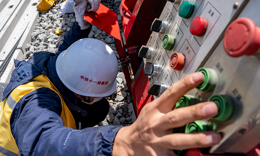 該項目部還增加了焊軌試驗頻率，通過為期13天的焊機調整參數工作，經過30根的落錘試驗才最終確定了焊機工藝參數。送檢到鐵科院的22根焊接鋼軌，一次性通過鋼軌外觀、落錘、探傷、靜彎、疲勞、拉伸、沖擊、硬度、宏觀、顯微組織及晶粒度、斷口檢驗等項目，型試試驗報告均為合格。圖為技術人員正在調整焊軌機位置。（丁慶濱 攝）