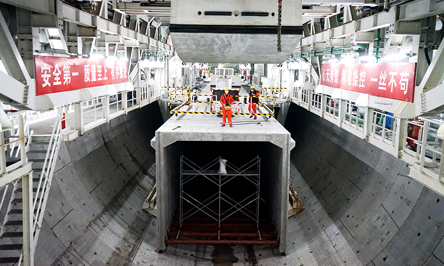 此次穿越北岸大堤成功克服了兩大難啃的“硬骨頭”。一是地面巨大的水土壓力，盾構機面對頂部最大43米的超深覆土施工，最大水土壓力達到5巴，這對盾構機和操作人員都是巨大的考驗，技術人員必須對盾構機的掘進參數實現精準操控，確保盾構機在控制水土壓力的技術要求范圍內連續推進。二是成功穿越鈣質結核全斷面粉質黏土復雜地層。圖為將管片運送至喂片機。