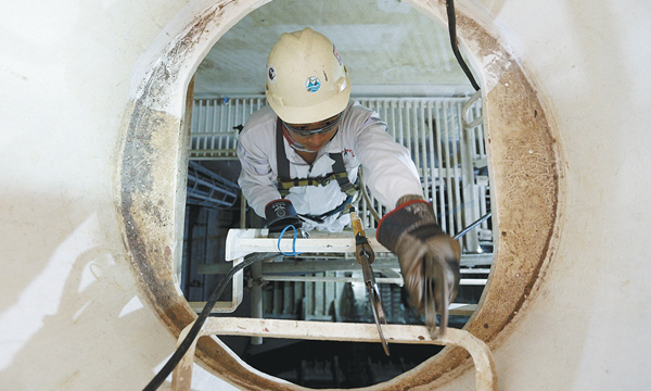 圖為施工人員正在通過直徑0.6米的入口進入P70壓載艙，由于艙內樓梯陡峭，施工人員每走一步都要格外小心。