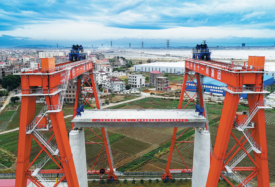 近日，由中國鐵建所屬中鐵十一局施工的新型40米高鐵箱梁穩穩落在福廈鐵路湄洲灣跨海大橋30米高的橋墩上，這是目前國內該種梁型架設的最高高度。為攻克高橋墩架梁施工難題，中鐵十一局為福廈鐵路研發制造了多臺新型高鐵箱梁架設設備，其中多項架梁技術運用均屬全國首創。圖為提梁機在進行落梁作業。（楊光 攝）