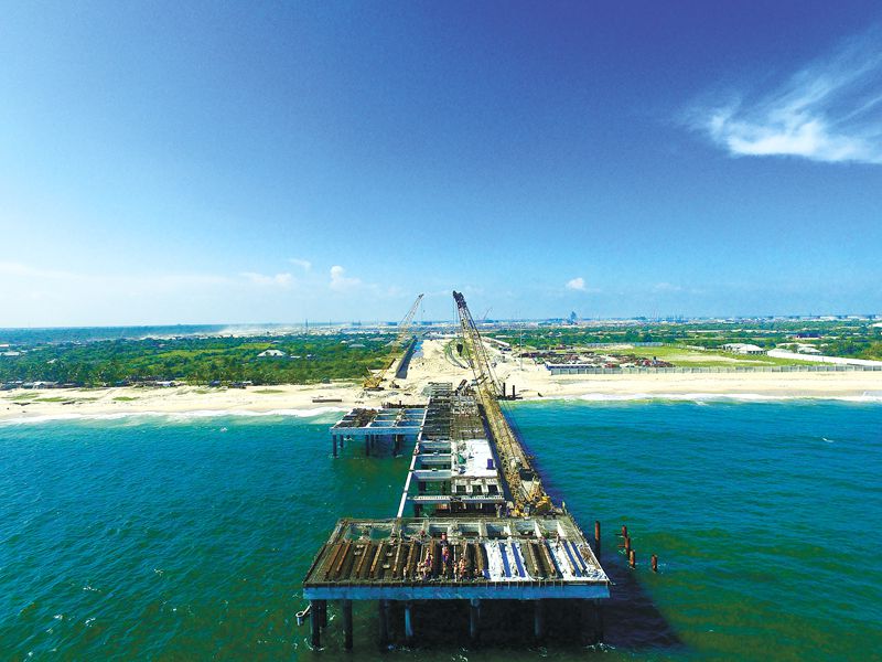 目前，中國海油所屬海油工程承包的尼日利亞DANGOTE項目接岸棧橋施工進入沖刺階段。與常規海管登陸形式不同，該項目在登陸點新建一座長約230米的鋼樁水泥棧橋，8根海管以整體立管形式登陸至棧橋，再通過棧橋上部管廊接入陸地閥門站。目前棧橋主體結構施工已全部完工。面對尼日利亞拉各斯海域復雜的天氣狀況，項目組采取相應安全措施，全力保障后續護岸結構、引橋道路等工作。圖為11月1日拍攝的現場施工圖。