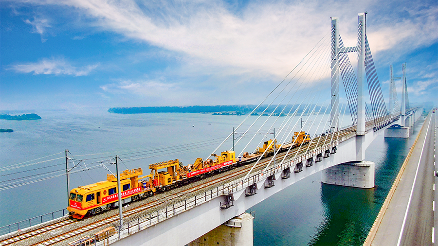 9月28日早上6時30分，首趟105節貨運列車滿載8400噸煤炭從浩勒報吉南站駛出，標志著世界上一次性建成并開通運營里程最長的重載鐵路——浩勒報吉至吉安鐵路（以下簡稱浩吉鐵路，即原蒙西至華中地區鐵路）開通運營。浩吉鐵路全長1813.5公里，北起內蒙古鄂爾多斯市浩勒報吉南站，終到京九鐵路吉安站。它的開通，改變了中國鐵路煤炭運輸格局，為我國鐵路版圖新增一條縱貫南北的能源運輸大通道。圖為中國鐵建電氣化局浩鐵路漢江特大橋上接觸網軌道車施工。