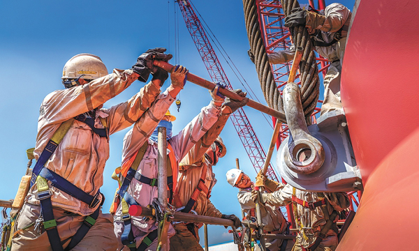 盡管如此，海油工程5000多名建設者卻是“38℃的高溫，100度的擔當”，“蒸”戰正酣。圖為大暑天氣里，吊裝用的工具曬得滾燙，幾名工人正在合力調整200噸卡環的角度。