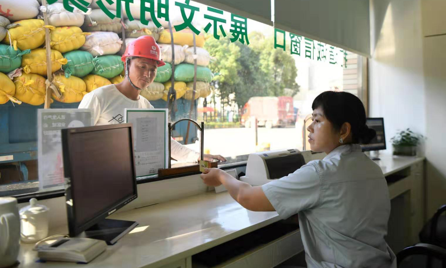 圖為7月30日，中儲糧寧鄉直屬庫工作人員從售糧者手中接過“一卡通”。中儲糧寧鄉直屬庫收購糧食全程使用“一卡通”業務信息系統，實現業務全流程監控，使收購流程更安全、高效。（新華社記者 薛宇舸 攝）