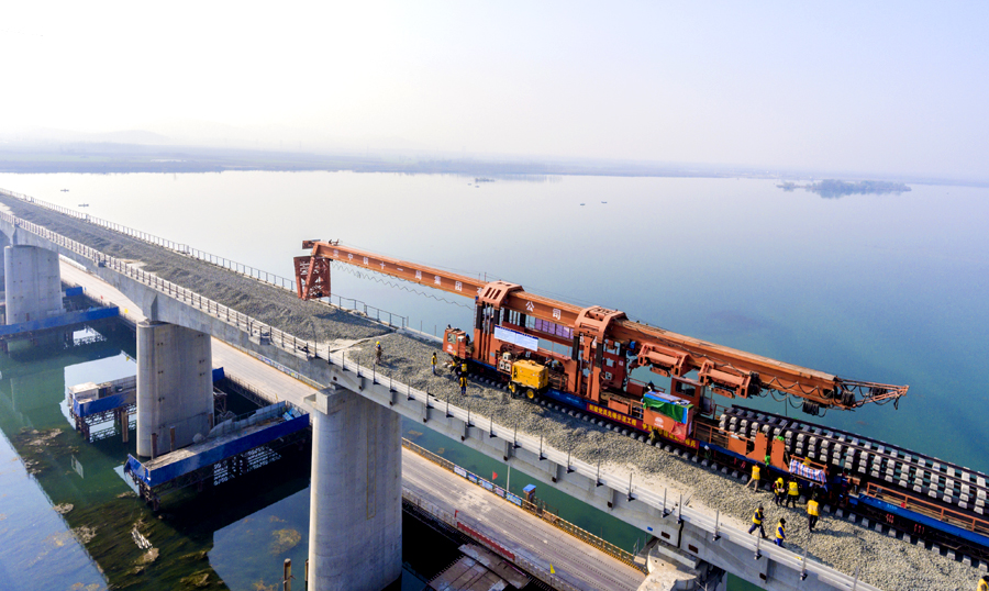 中鐵十九局蒙華鐵路鋪架4標建設者使用CPG500型鋪軌機，并結合采用單枕連續作業、長鋼軌鋪設和軌枕布設同步進行等方式，提高施工作業效率。中鐵十一局在傳統重載梁鋪架的基礎上進行技術創新，首次采用便于安裝拆除檢修的IIFC16型軌枕等諸多全新技術和工藝，確保線路質量和鋪軌安全。圖為蒙華鐵路湖北段鋪軌過漢江。