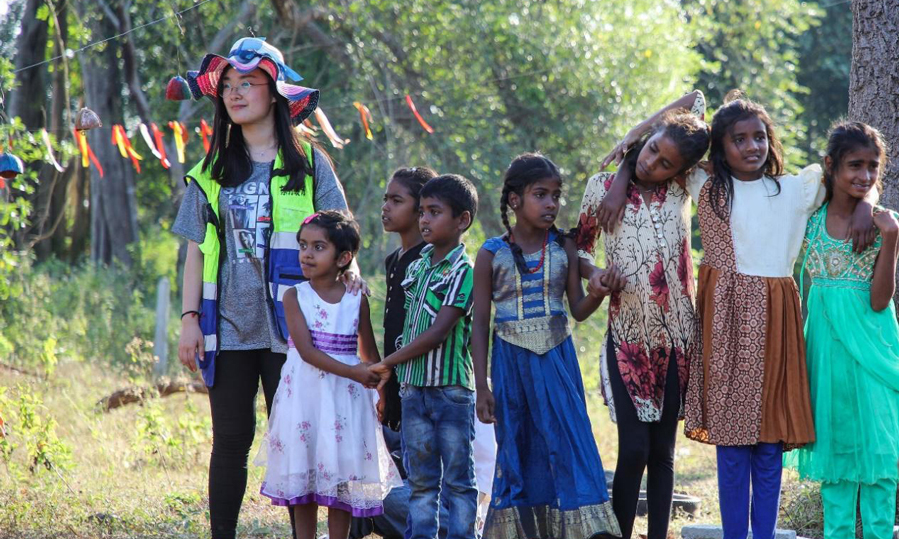 清華大學建筑學院學生郭世玉(左一)帶著當地兒童在公益課堂建設現場外的空地游戲。