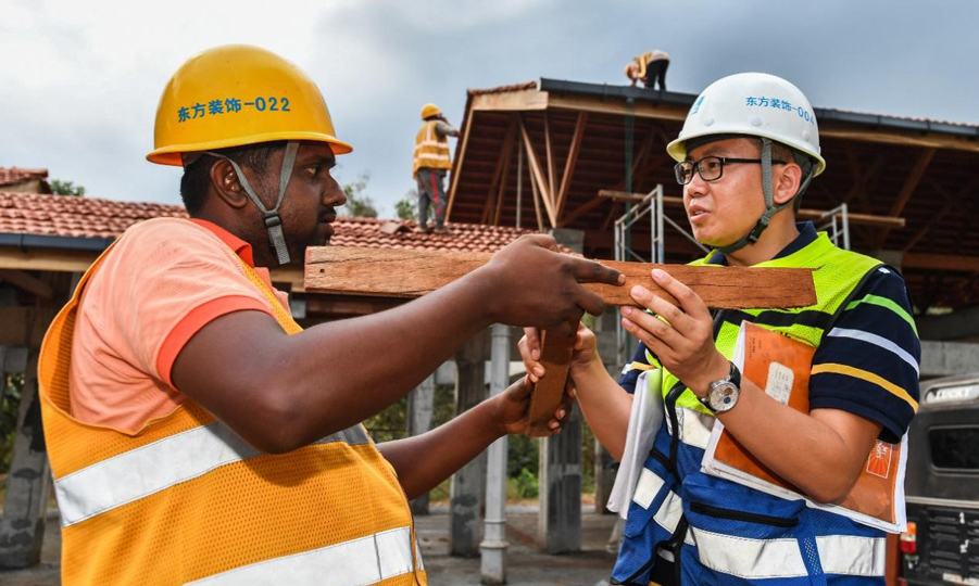 胥超(右)給當地工人的負責人講解木結構的構造原理。