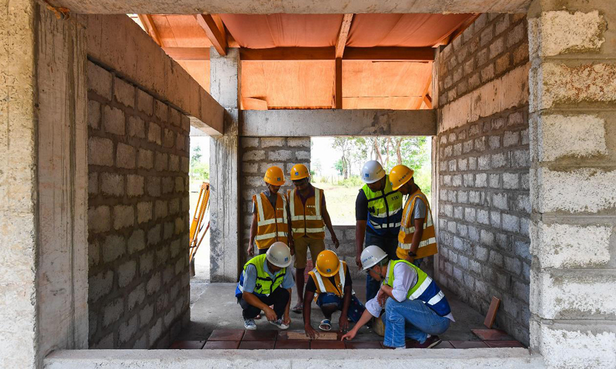 胥超(前右)正教授Pramod(前中)等當地青年如何貼地磚。