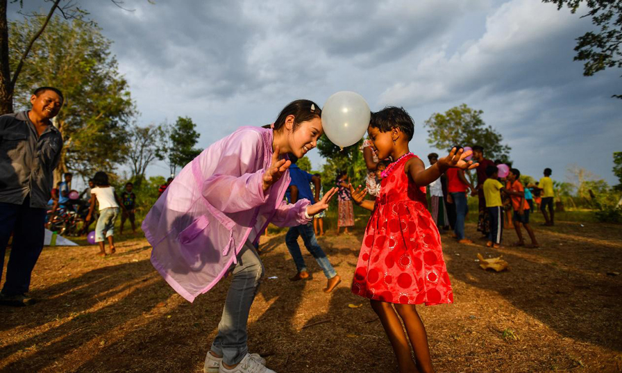 項目團隊成員劉利(左前)在聯歡會上和當地兒童一起游戲。