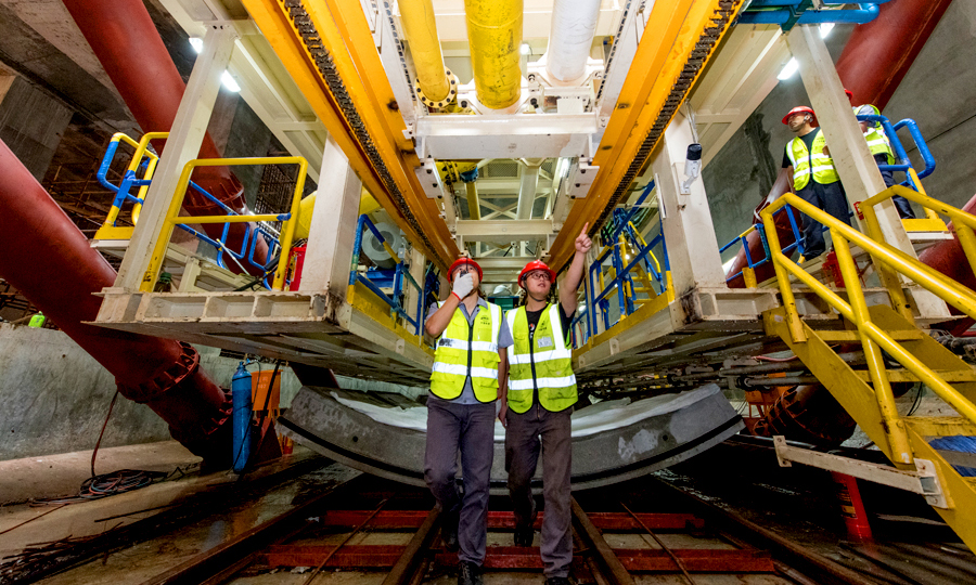 近日，中國鐵建所屬中鐵二十二局軌道公司廣州地鐵18號和22號線項目通過加長洞門鋼環寬度，在鋼環內圈安裝盾尾密封刷進行注脂，實現了洞門雙重止水效果，有效克服了廣州市富水沙層盾構始發的技術難題。日前，該項目部首臺大直徑泥水盾構機始發。圖為技術人員在討論解決方案。（桂天奇 攝）