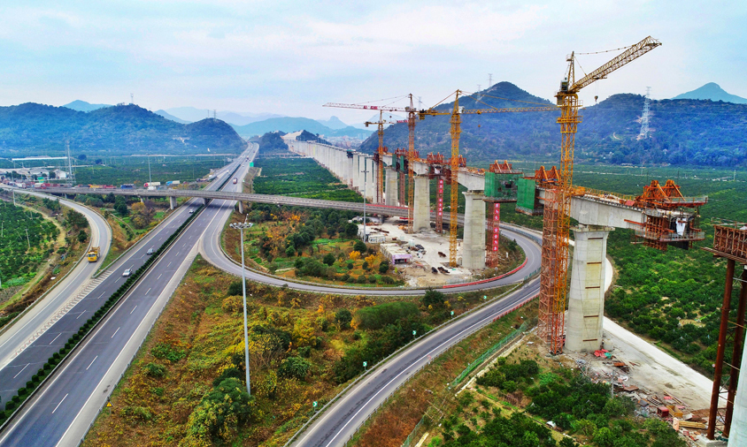 靈江特大橋上跨靈江航道、馬上線公路、S327省道、臺金高速公路，施工環境異常復雜，是全線關鍵性重難點控制工程。該橋在施工中不但要保證靈江及相鄰公路的正常通航通行、還面臨著深水基礎施工、大跨度連續梁施工線形監控等一系列施工難題。特別是位于靈江中的61-67號墩，鉆孔深度達95.945米。當鉆孔深度超過80米后，尤其在軟硬交互地層，控制樁孔的豎直度就成為一項重要的技術難題。由于樁孔直徑大、深，且存在較厚卵石層，非常容易造成護壁泥漿失效、孔壁局部或整體坍塌。因此，靈江特大橋施工也被稱為“在刀刃上跳舞”。圖為靈江特大橋連續梁合龍施工。