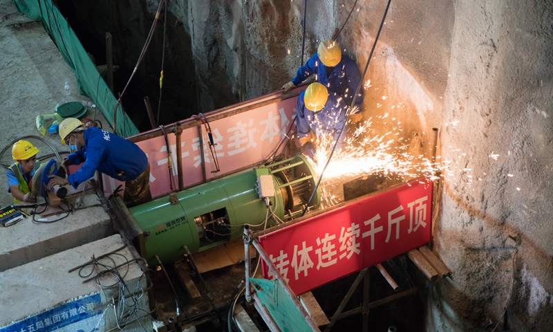 整個轉體過程需要在鐵路部門給定的“封鎖天窗點”內完成，為了不影響鐵路的正常運營，跨越鐵路的主橋采用轉體法施工。先平行于鐵路線路外澆筑梁體，最后該橋長160米、重1.8萬噸的T構梁體在兩臺千斤頂及牽引索的拉動下，以平均每分鐘1度的速度，歷時2個多小時旋轉120度至設計位置，順利完成轉體。圖為工人切割鋼絞線。（吳盛洋 攝）