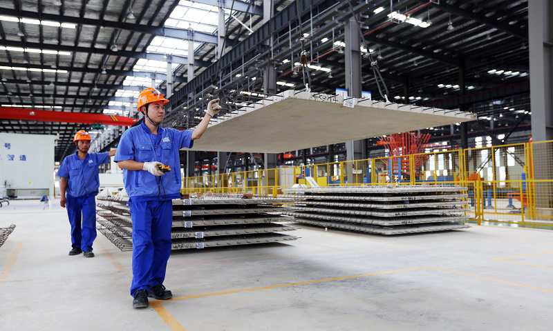 圖為建筑工人通過機械化作業，將一塊塊“樓板”運送至運輸車上。