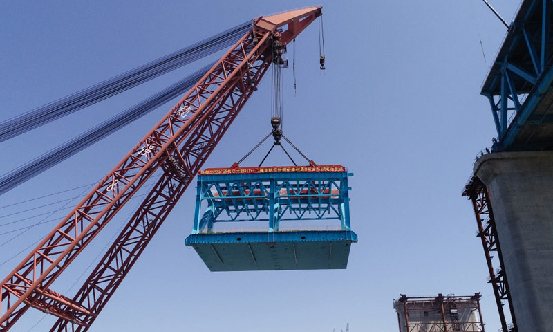 6月1日，隨著重達1210噸的大節段鋼梁吊裝到主航道橋31號墩墩頂，由中鐵大橋局施工的滬通長江大橋首個超千噸大節段鋼梁提前架設成功。圖為施工人員在使用浮吊吊裝、架設滬通長江大橋首個超千噸大節段鋼梁。（新華社記者 李響 攝）