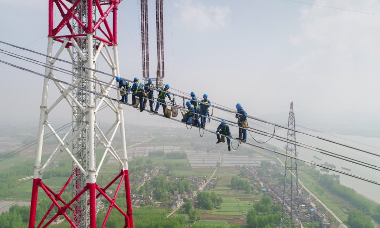 4月15日，在安徽省無為縣高溝鎮，工人們在昌古特高壓長江大跨越工程跨越塔導線上進行高空作業（無人機拍攝）。
