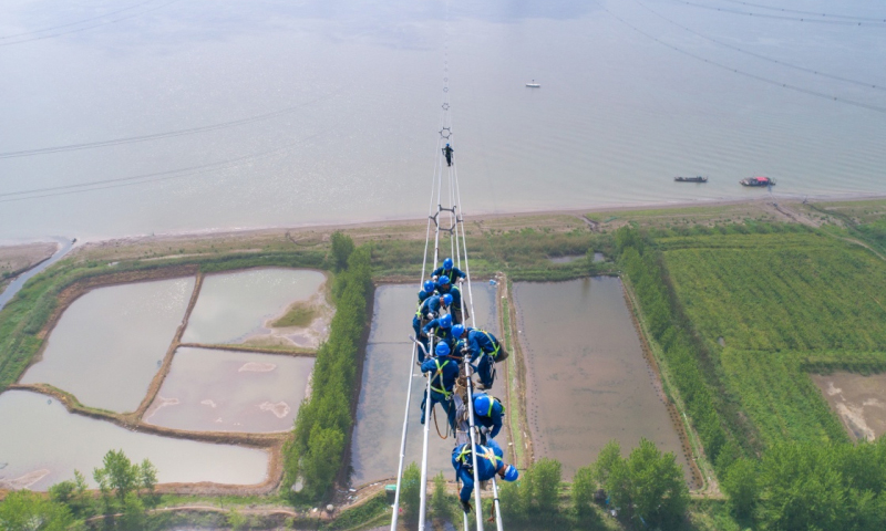 4月15日，在安徽省無為縣高溝鎮，工人們在昌古特高壓長江大跨越工程跨越塔導線上進行高空作業（無人機拍攝）。