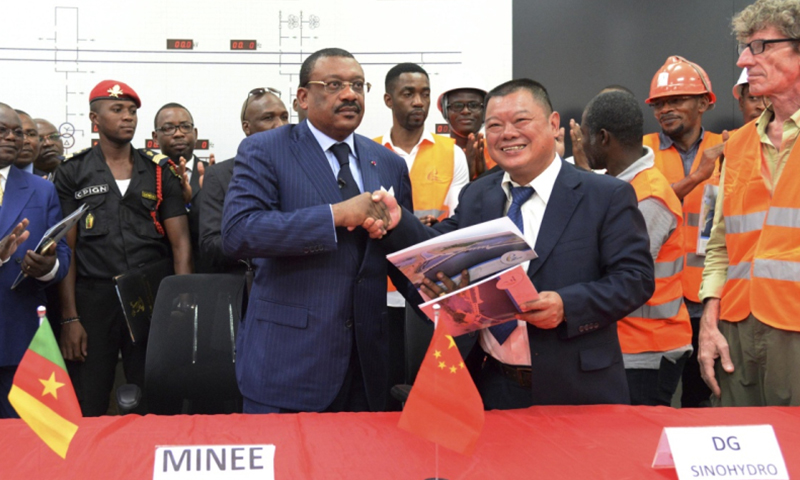 2月8日，在位于喀麥隆南部大區的曼維萊水電站，喀能源與水資源部長巴西勒·阿坦加納·庫納（中左）和曼維萊水電站項目經理陳高（中右）簽署項目驗收文件后握手。由中企承建的喀麥隆曼維萊水電站主體部分8日通過喀方臨時驗收委員會驗收。該項目位于喀麥隆南部大區，總投資6.37億美元，總裝機容量211兆瓦。項目于2012年底開工，由中國電力建設集團總承包，中國水利水電第16工程局實施。（新華社記者 喬本孝 攝）