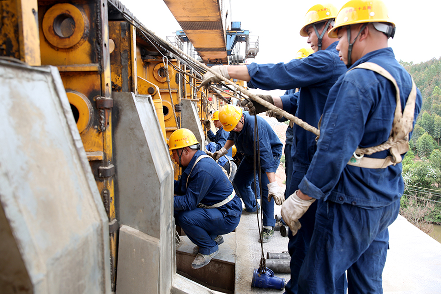 落梁吊裝過程需要40分鐘，精準對位時間占了一半。裝吊工分工協作，拿著水平尺測量支座平整度，用吊錘評估支座和中心、墩臺的錯動量，用鋼尺測量四角高差……每道工序都不能少，嚴謹的工作態度才能確保每一榀箱梁精準吊裝到位。圖為作業人員為架橋機過孔做準備工作。（黃詩偉 攝）