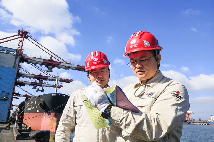 圖為除夕值班的國家能源集團珠海港務生產部計劃科李吉平和商務科鐘楊，他們在裝船機旁查驗裝船噸量，做到心中有數、顆粒歸倉，保障煤炭穩定供應。（李勇 攝）