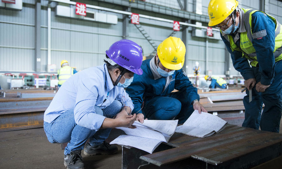 近日，中核華興鋼結構管理部濱江基地集約化加工車間正為國核示范項目40附屬廠房鋼柱和鋼梁的預制加工而忙碌著，鉚工組長李來軍在組對鋼柱連接牛腿時，發現按照深化設計圖紙的定位尺寸無法組對。技術主管高莉靈和李來軍仔細查看藍圖，核算尺寸，解決問題。技術指導施工，技術結合施工，施工反饋技術是一個良性循環，也是閉環正反饋效應。（范錦紅 攝）