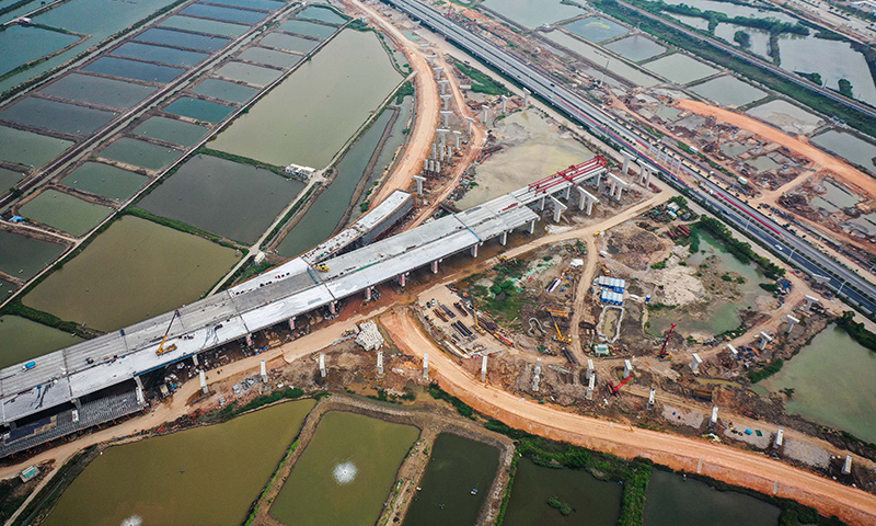 近日，中鐵十一局建設者在珠海鶴港高速公路二期工程高欄港樞紐立交橋加緊施工，目前已開始對接江門黃茅海大橋陸上引橋。圖為5月1日拍攝的珠海鶴港高速公路二期工程高欄港樞紐立交橋建設現場。（新華社記者 劉大偉 攝）