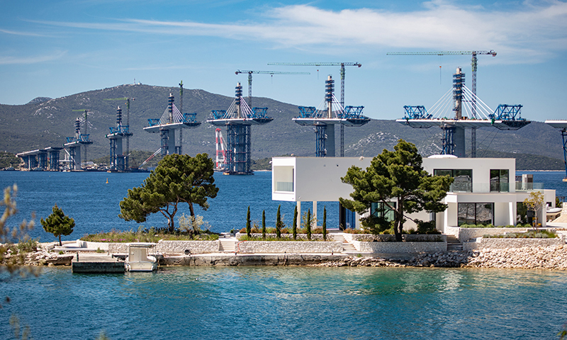 佩列沙茨跨海大橋項目由中國路橋公司牽頭的中國企業聯合體于2018年中標后開工，大橋設計總長2440米，建成后將橫跨亞得里亞海小斯通灣，連接隔海相望的克羅地亞領土。目前該項目的施工進度穩步推進。圖為5月10日在克羅地亞南部的科馬爾納村附近拍攝的大橋施工現場。新華社發（耶拉維奇 攝）