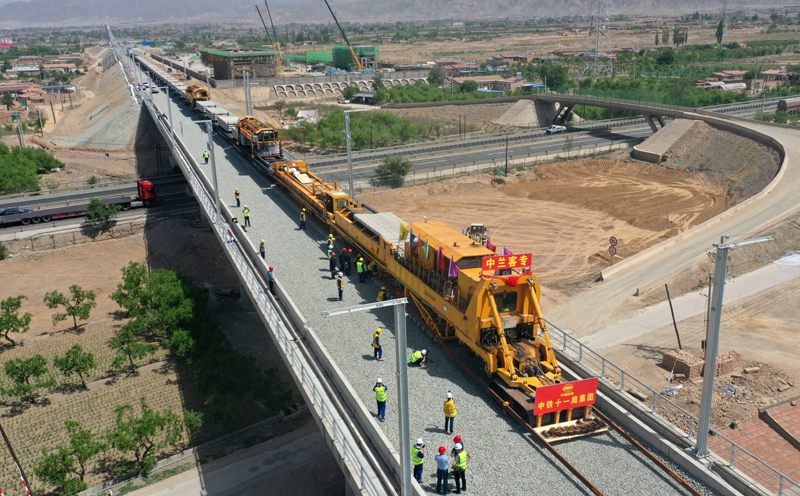 5月30日，在中（衛）蘭（州）客專平川站外新墩特大橋上，中鐵十一局施工人員駕駛鋪軌機將首對鋼軌鋪設到軌枕上，這標志著甘肅省首條控股建設的鐵路客運專線——中蘭客專甘肅段進入鋪軌施工階段。圖為當日，中鐵十一局建設者操作CPG500型鋪軌機在中蘭客專甘肅段新墩特大橋上進行鋪軌作業。（新華社記者 陳斌 攝）