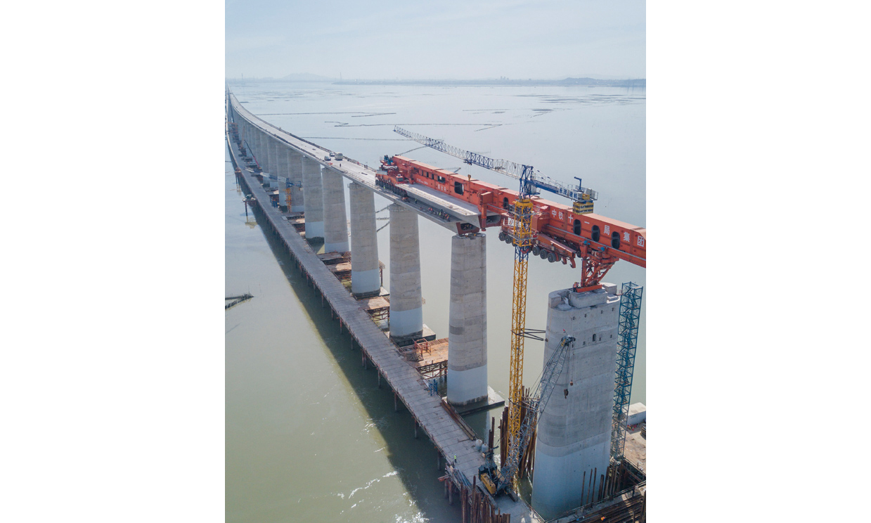 7月11日，我國自主研發的“昆侖號”千噸級運架一體機在中鐵十一局承建的新建福廈鐵路湄洲灣跨海大橋建設現場，圓滿完成最后一孔40米高鐵箱梁架梁任務。接下來，在經過拆解、運輸、組裝之后，這臺體現我國高鐵橋梁架設最先進技術的大國重器將在浙江參與杭衢鐵路的建設。圖為在新建福廈鐵路湄洲灣跨海大橋建設現場，“昆侖號”在架設該線路最后一孔40米箱梁。（新華社記者 宋為偉 攝）
