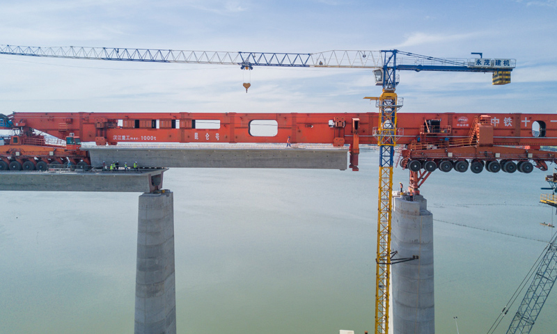 圖為7月11日，在新建福廈鐵路湄洲灣跨海大橋建設現場，中鐵十一局工人協同“昆侖號”千噸級運架一體機架設該線路最后一孔40米箱梁。（新華社記者 宋為偉 攝）