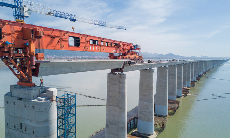圖為7月11日，在新建福廈鐵路湄洲灣跨海大橋建設現場，中鐵十一局工人協同“昆侖號”千噸級運架一體機架設該線路最后一孔40米箱梁。（新華社記者 宋為偉 攝）