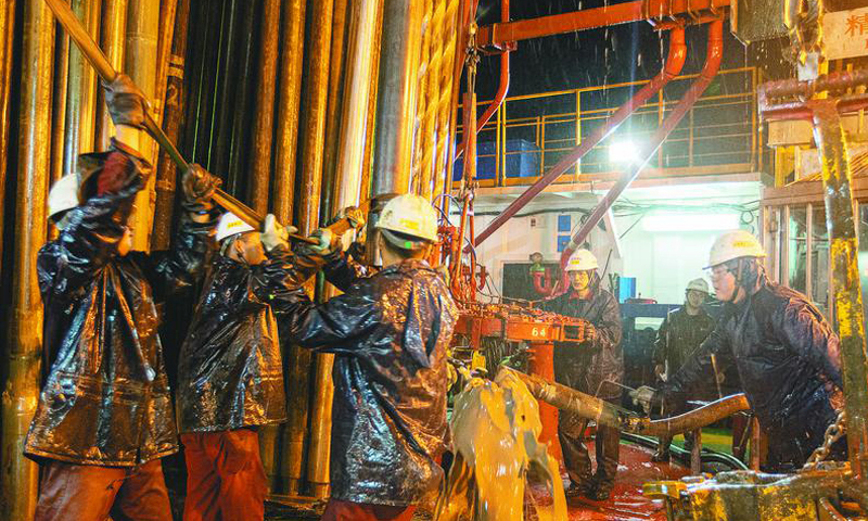 近日，在中國海油“新優快”墾利16-1試點項目現場，工作人員加緊施工，呈現出熱火朝天的生產景象。截至7月12日，已完成18口井鉆井和8口井完井作業，較設計節省工期73.49天。目前，“新優快”第二階段鉆井作業正在推進中。圖為現場作業人員冒雨拆甩出井鉆具作業。